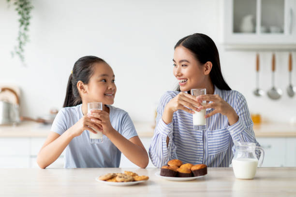 pretty-asian-teen-girl-drinking-milk-with-her-mom-sitting-at-kitchen-table-having-pleasure-1756107280650657113775.jpg
