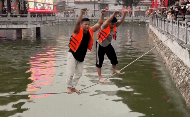 Nín thở từng giây xem gymer gần 100kg đi trên dây giữa hồ nước lạnh buốt ở hội làng ngày tết - Ảnh 1.