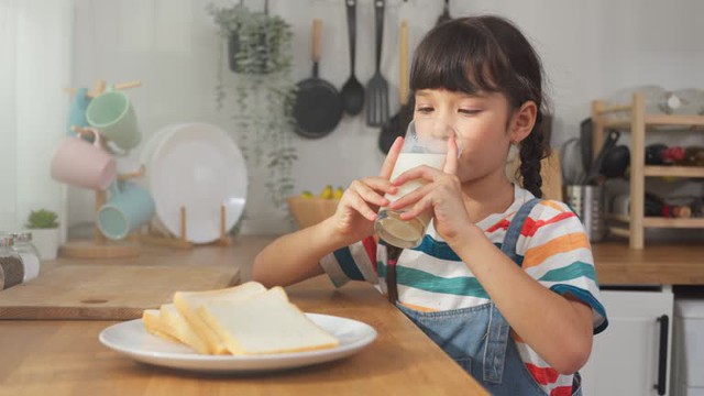 caucasian-kid-holding-a-cup-of-milk-and-drinking-in-kitchen-at-home-young-preschool-girl-or-17561072233792097450258.jpg